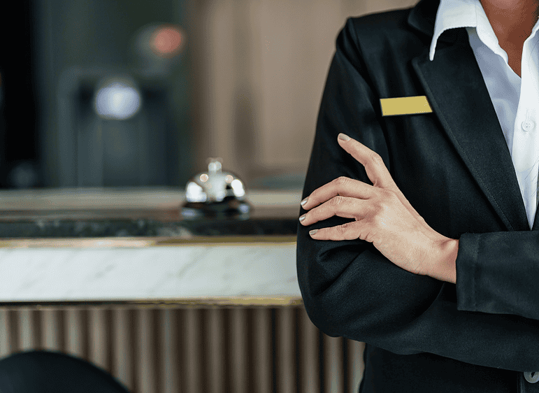 Hotel staff member in uniform at reception desk for sports team visits.