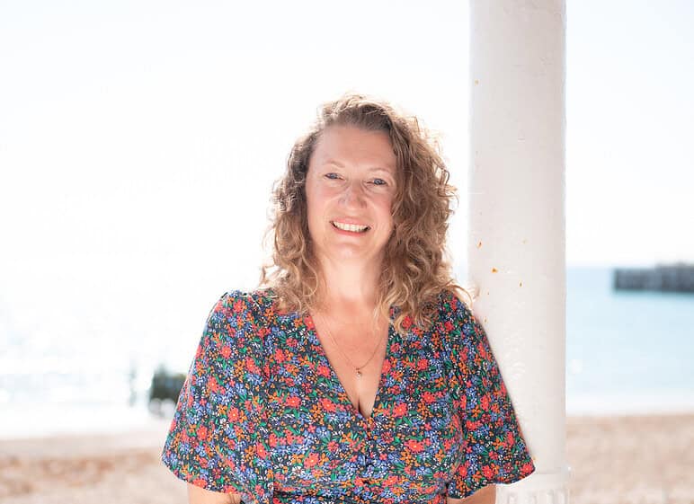 Smiling woman in floral dress at Travel Places staff feature.