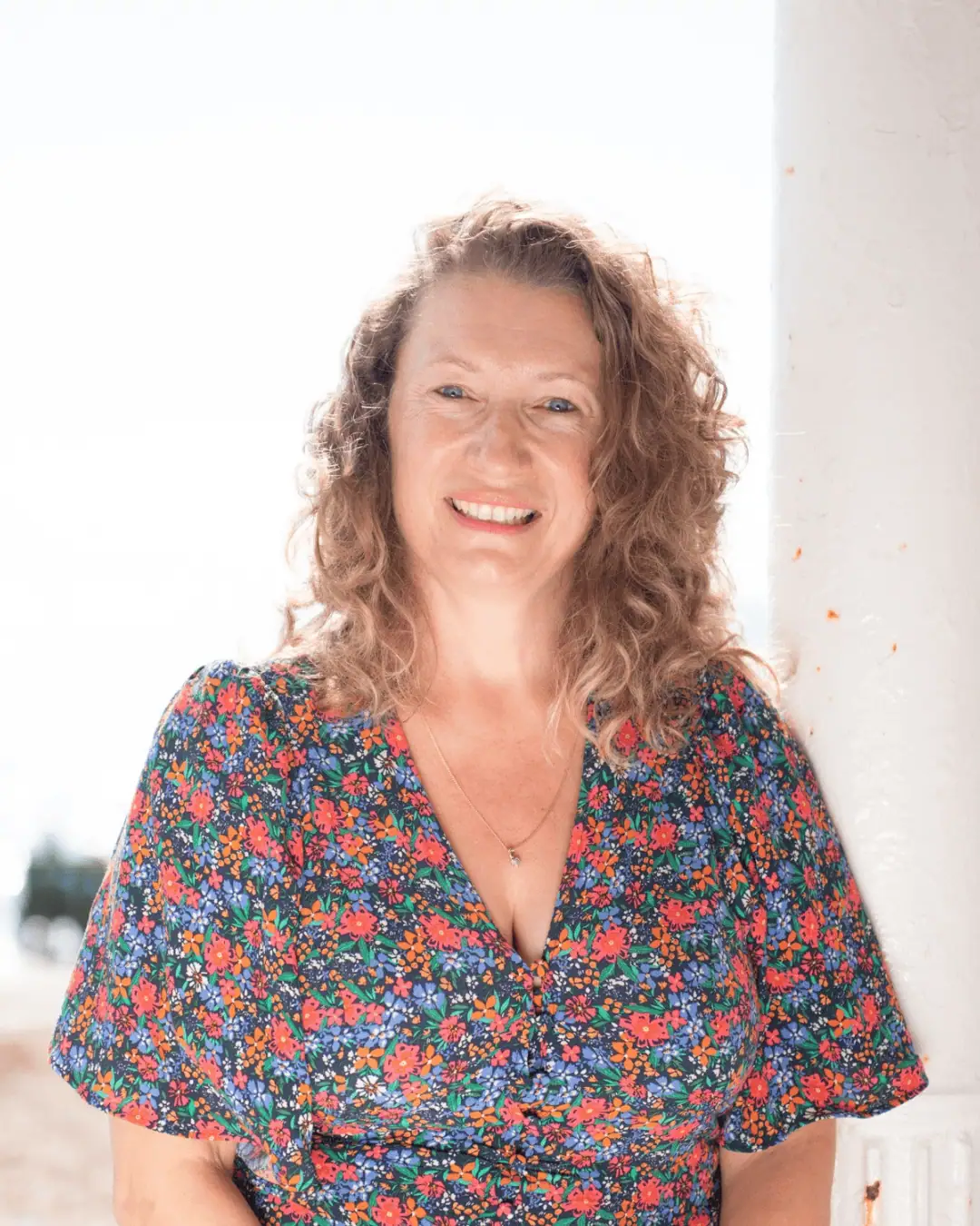 Smiling woman in floral dress at Travel Places staff feature.